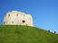 Clifford Tower, part of the fortification of York Castle, with young boys climbing up grassy hill, York.