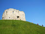 Clifford Tower, part of the fortification of York Castle, with young boys climbing up grassy hill, York.