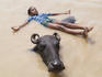 Young boy playing with a water buffalo in the Ganges River.