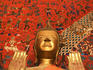 Buddha statue at Wat Xieng Thong, standing in front of mural.