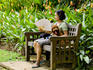 Woman fanning herself with dog on bench at Singapore Botanic Gardens.