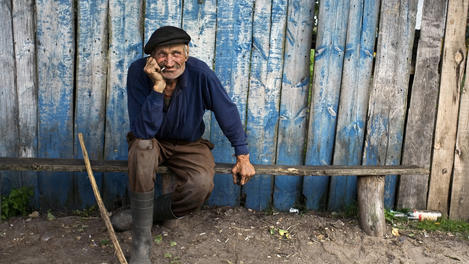 Elderly man sitting in front of his house after a day of hard work in the field, Palesse region.