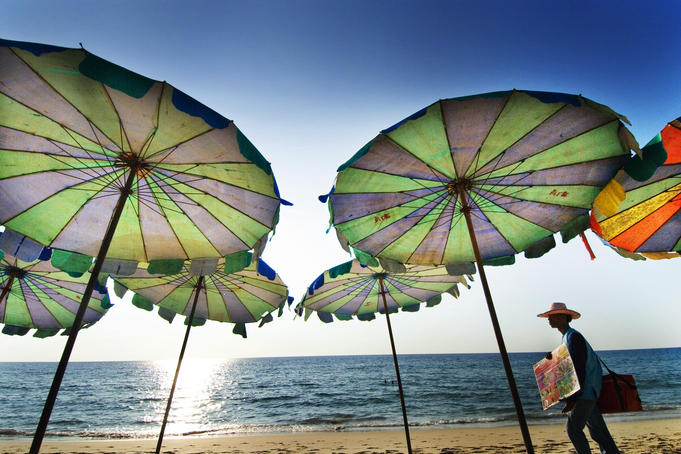 Ice-cream seller walking by beach umbrellas, Surin Beach.