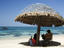 Relaxing under a thatched beach umbrella.