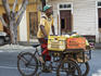 Produce vendor pedalling through the streets on bicycle.