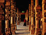 Young woman walking through sandstone pillars at Qutb Minar complex.