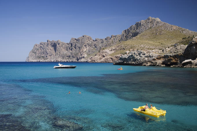 Paddleboat and luxury yacht in Cala Sant Vicenc bay.