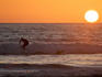 People surfing at late afternoon as the sun sets.