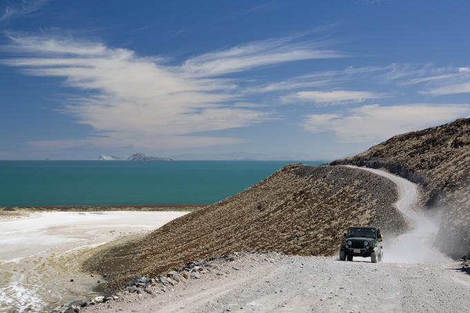 Pick-up truck driving on dirt road near salt flats at Sea of Cortez coastline south of Puertecitos.