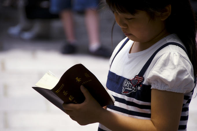 Young girl reading a Chinese Bible at Community Church.