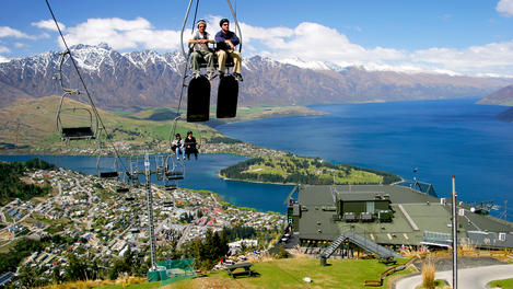 Luge riders taking lift up to top of hill, looking out over Queenstown and Lake Wakatipu.