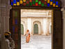 Palace guard and cleaner framed in doorway at Mehrangarh Fort.