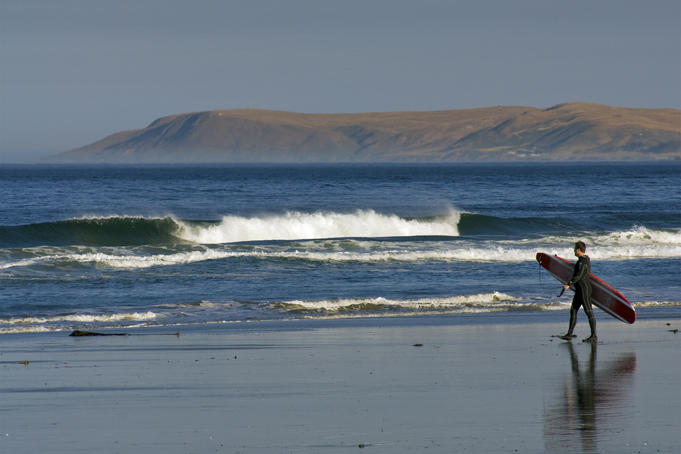 Surfer walking on Morro Strand State Beach.
