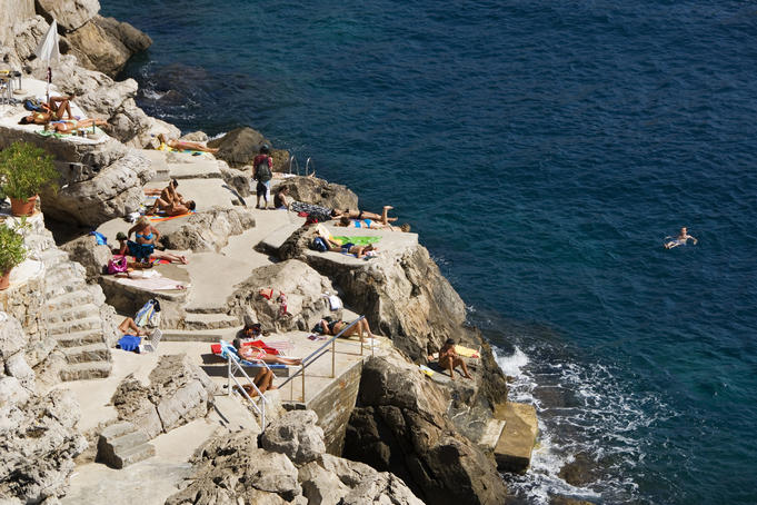 Swimmers and sunbathers enjoying the rocks outside the south wall.
