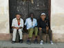 Portrait of three elderly men sitting on a doorway step.