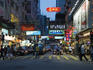 Busy pedestrian walkway and street scene at dusk.