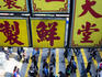 Busy pedestrian crossing, with overhanging signs.
