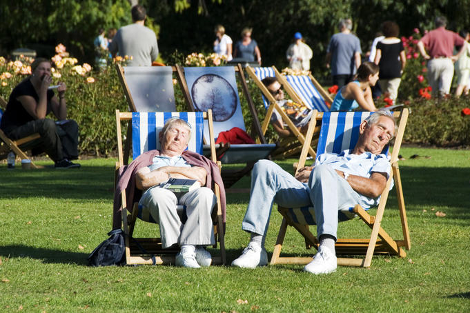 Couple sleeping on deckchairs in the sun, Regent Park, London.