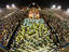 Samba schools parading towards the bird-shaped Sambodrome icon during Carnival.