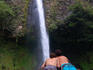 Couple of men laying on rock and viewing waterfall near city of Arenal.