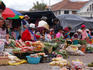 Vendors selling fruits and vegetables at outdoor market.