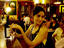 Waitress with wine bottle and two glasses preparing to attend table inside Cafe Buenos Aires restaurant, Baixa (downtown) district.