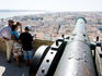 Visitors looking over downtown panorama and River Tagus, from old cannon on walls of Castelo de Sao Jorge.