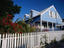 A pale blue wooden house with a white picket fence