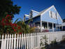 A pale blue wooden house with a white picket fence
