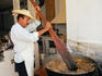 A man preparing carnitas (stewed pork) with what looks more like an oar than an ordinary kitchen utensil, for a Quinceanera (girls fifteenth birthday) celebration.