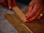 Hands of an artisan making a measurement with a wooden ruler on a pair of lederhosen in the Lederhosen Workshop at the Atelier Mahla - Munich, Bavaria