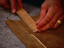 Hands of an artisan making a measurement with a wooden ruler on a pair of lederhosen in the Lederhosen Workshop at the Atelier Mahla - Munich, Bavaria
