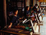 Women weaving on traditional looms in workshop producing traditional Ikat and Songket woven fabrics.