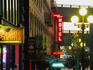 Cafe signs and others, lit up as dusk approaches on Yesler Way near Pioneer Square