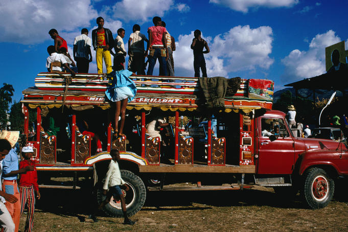 People standing on roof of crowded intercity bus.