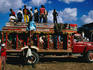 People standing on roof of crowded intercity bus.