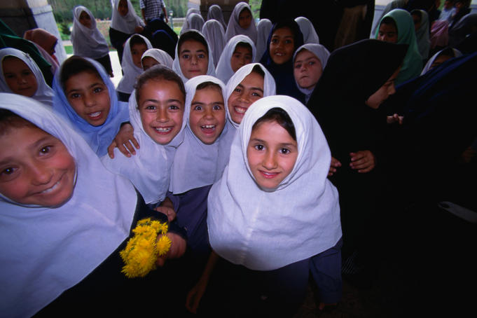 Young local schoolgirls in required uniform smile in Tehran