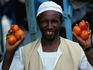 A tomato vendor with his hands full.