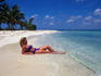 A woman sunbathing in the shallows on a sandy beach on one of the cayes off the coast of Belize
