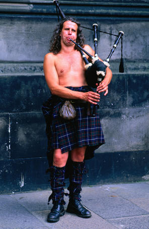 A busker in full regalia blowing his pipes in Edinburgh, Scotland