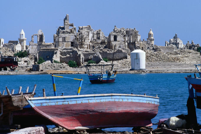 Boat with ruined coral port of Suakin in distance.