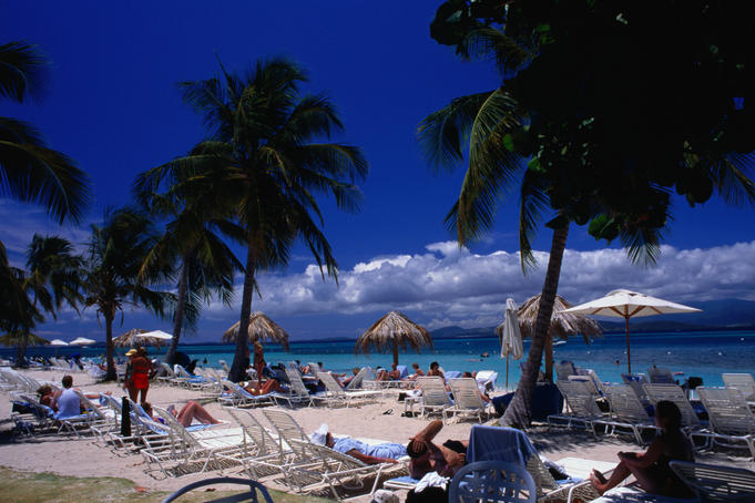 Tourists relaxing on beach.
