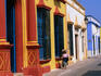 Woman walking past colourful house facades on street.