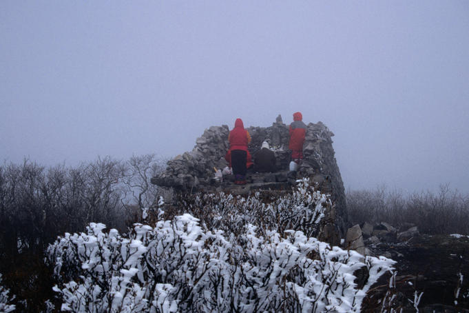 People praying at the snowy Cheonjedan Altar on Taebaeksan mountain, which means 'Big White mountain'. The mountain is one of three sacred peaks to Korean Shamanists.
