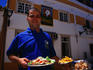 Alfresco dining: waiter with Chicken Piri-piri outside the restaurant in Guia.