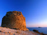 Golden light of a setting sun striking the ruins of a cliff-top watchtower at the Punta de l'Escaleta near Benidorm.