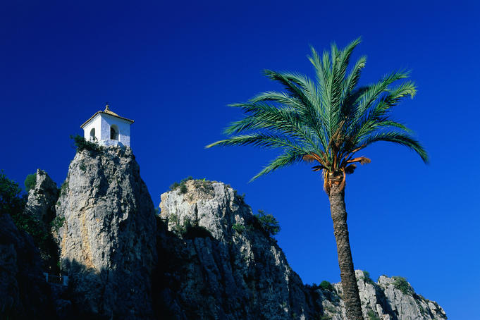 Clifftop bell-tower with palm tree in foreground, at Guadalest in the Alicante region.