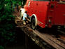 Man moving planks to help a fire truck cross a bridge.