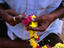 A flower seller from Hyderabad threads a garland of chrysanthemums