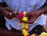 A flower seller from Hyderabad threads a garland of chrysanthemums